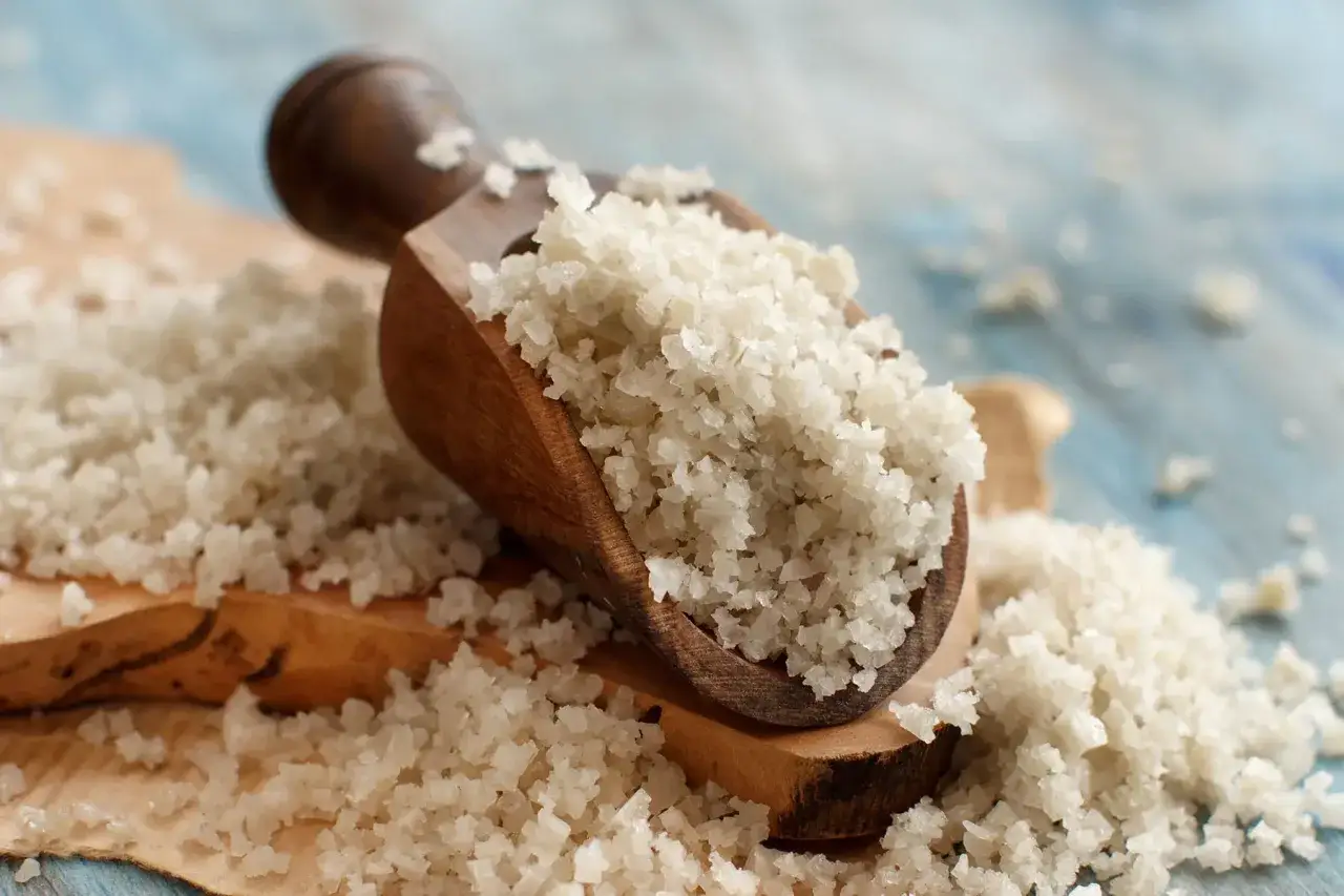 Drewniana łyżka pełna kryształk&oacute;w soli kamiennej, idealna do przyprawiania potraw. S&oacute;l kamienna zastosowanie w kuchni.