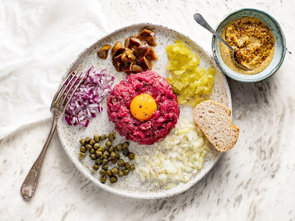 Tatar wołowy na talerzu z dodatkami