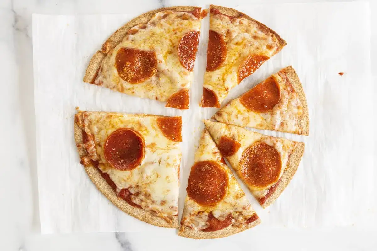 Pyszna pizza na tortilli z serem i pepperoni, pokrojona na kawałki. Idealna na szybką przekąskę.