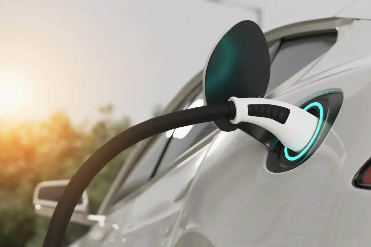 Biały samochód elektryczny z niebieskim podświetleniem portu ładowania, gotowy do podróży na długie dystanse.