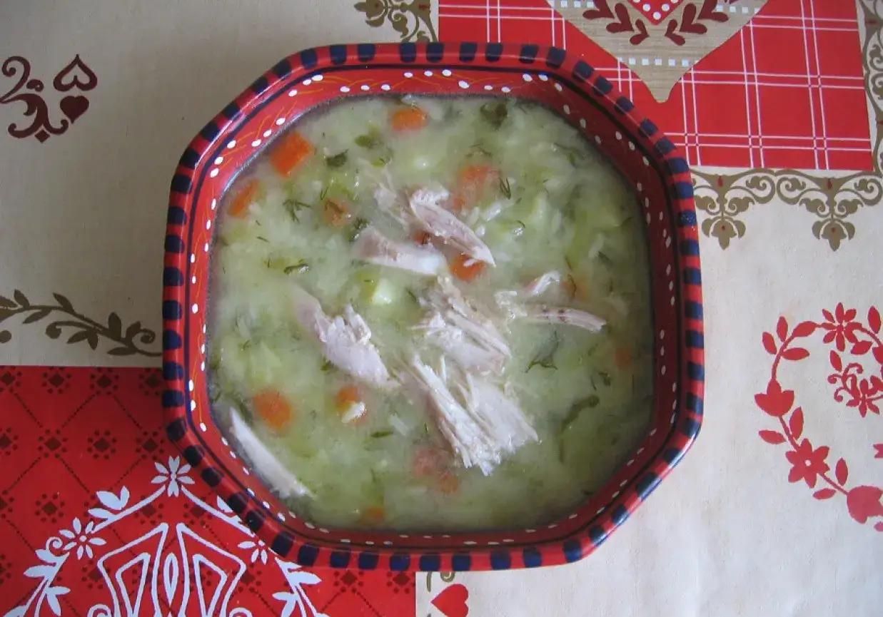 Zupa og&oacute;rkowa z ryżem, kawałkami kurczaka i marchewką w ozdobnej misce.