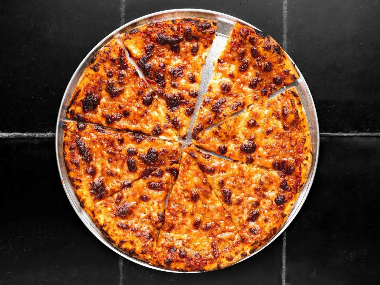 Pyszna, gorąca pizza z ciągnącym się serem, pokrojona na 8 kawałków. Idealna na wspólne spotkanie, bo ile piec pizze, tyle radości!