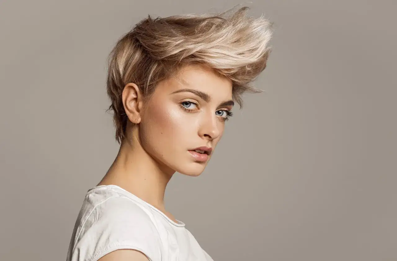 Kobieta z blond, potarganą, kr&oacute;tką fryzurą, prezentująca najnowsze kr&oacute;tkie fryzury damskie.