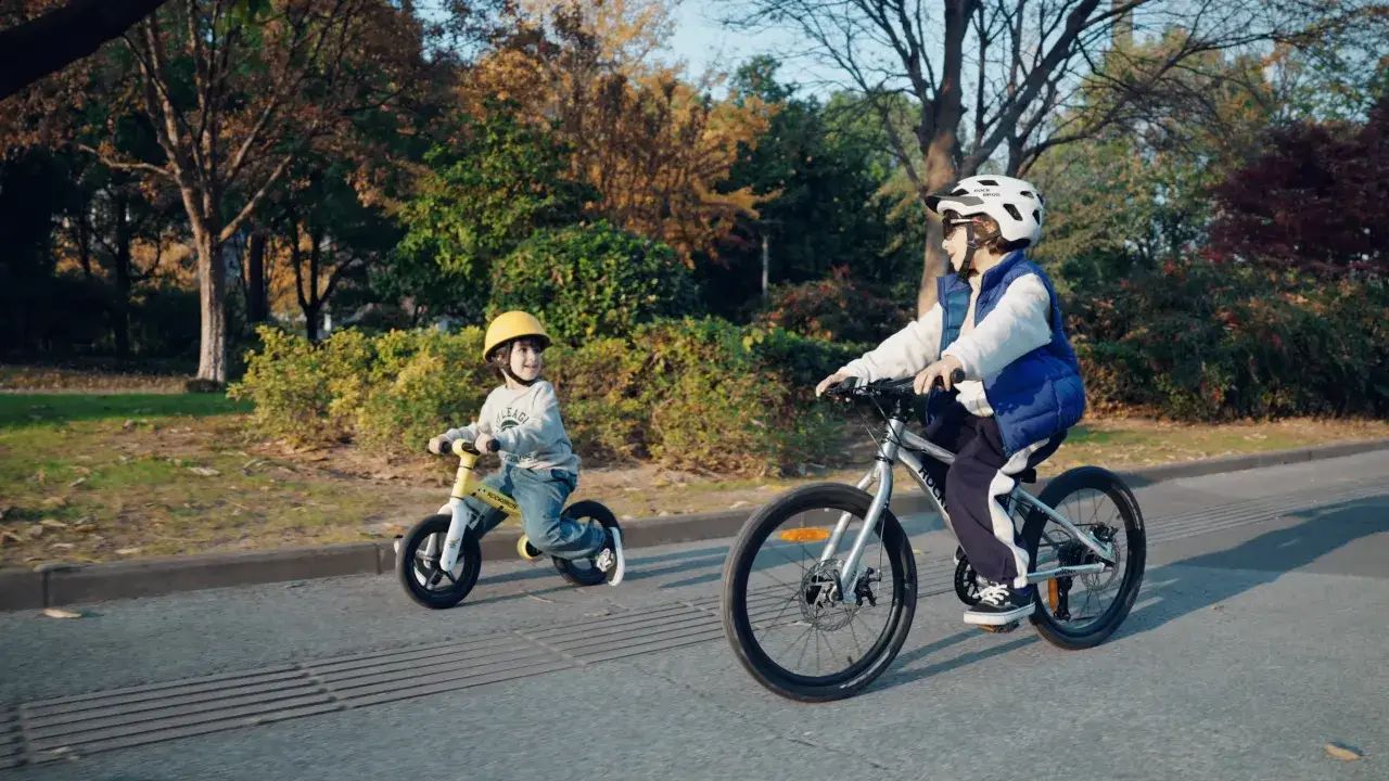 Dzieci na rowerach ROKO BIKES cieszą się jesiennym dniem w parku.