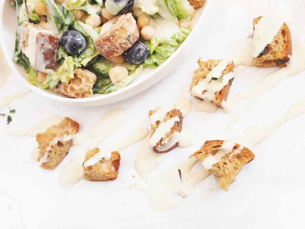 Pyszna sałatka z grzankami i parmezanem, polana kremowym sosem. Chrupiące grzanki i świeże warzywa tworzą idealne połączenie.