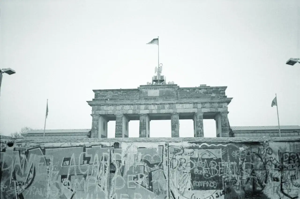 Brama Brandenburska nad murem pokrytym graffiti, widok z Berlina Zachodniego, kiedy postawiono mur berliński.