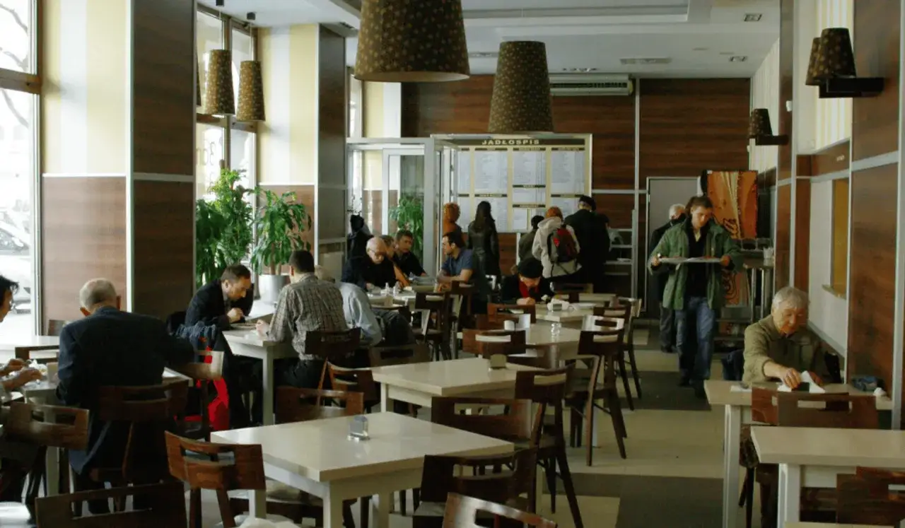 Ludzie jedzą obiad w restauracji w Warszawie. Widać menu, stoliki i krzesła.