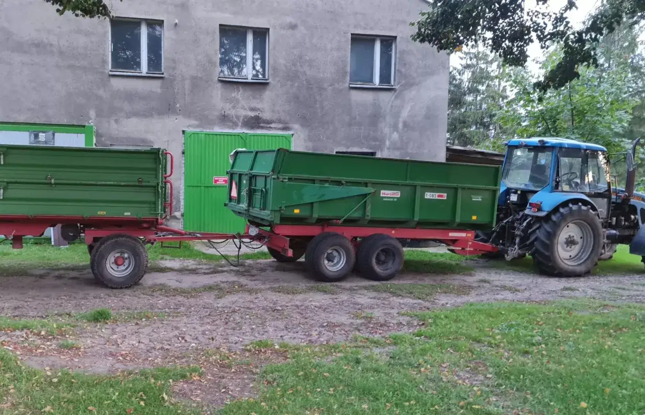 Niebieski ciągnik z przyczepą, gotowy do pracy. Czy na kat B można jeździć ciągnikiem z przyczepą? To zależy od masy zestawu.