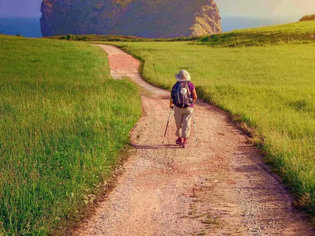 Pielgrzym idzie ścieżką w stronę morza, marząc o Santiago de Compostela. Szlak z Polski jest długi, ale widok wynagradza trudy.
