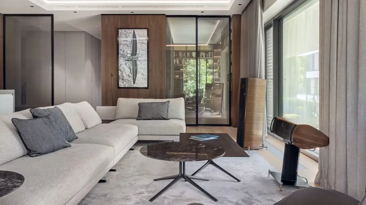 Nowoczesny salon z szarą kanapą, marmurowym stolikiem i przeszklonym gabinetem. Piękne nowoczesne wnętrza z drewnianymi akcentami.