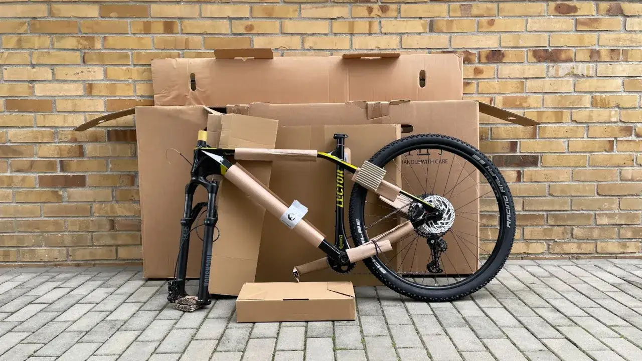 Części roweru w kartonach, gotowe do składania. Rama, widelec i koło czekają na montaż.