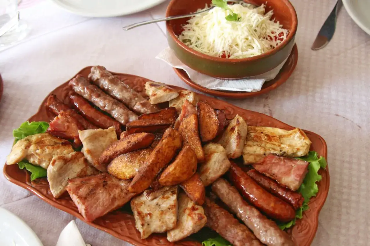 Talerz pełen mięsnych przysmak&oacute;w, idealny na ucztę w stylu kuchnia serbska: kiełbaski, cevapcici, grillowany kurczak i ziemniaki.