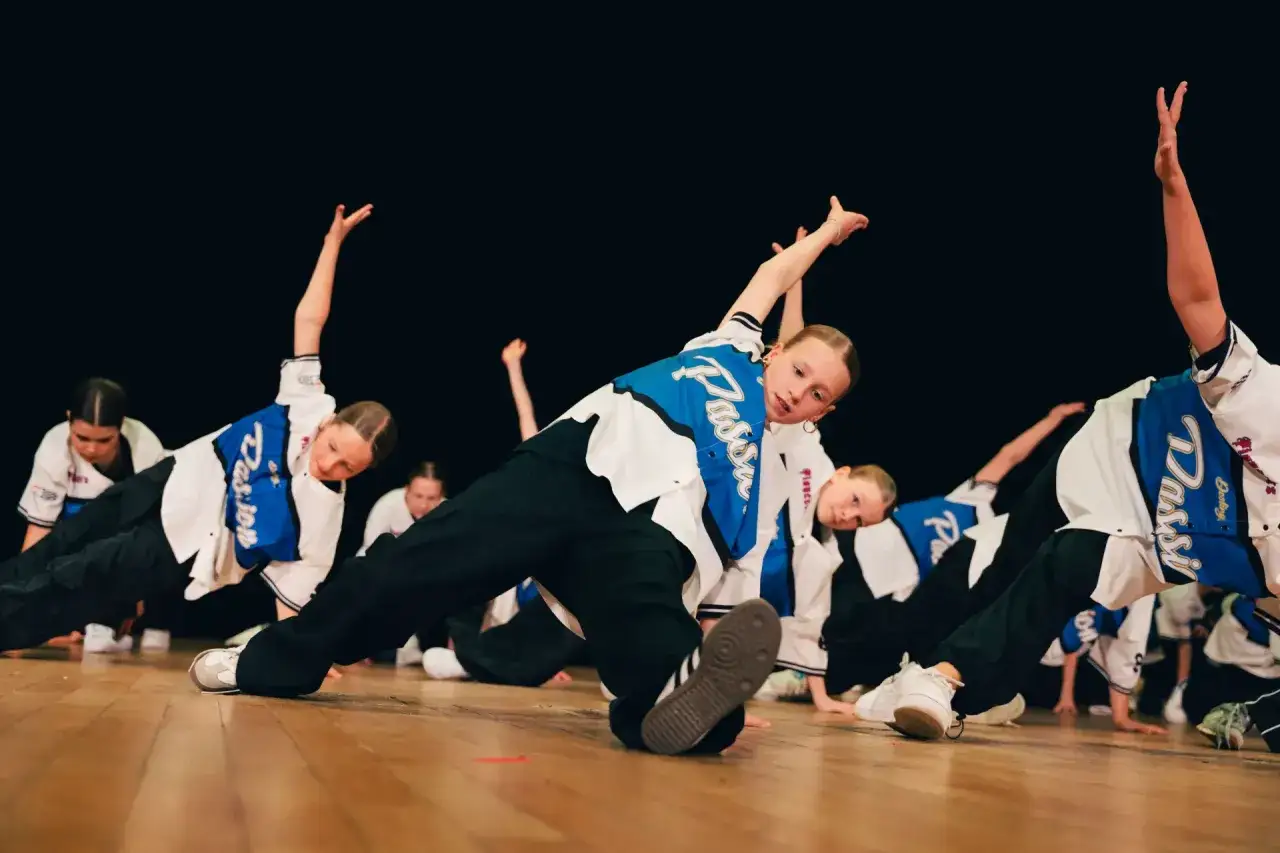 Dzieci wykonują energiczne piosenki z układem tanecznym na scenie.