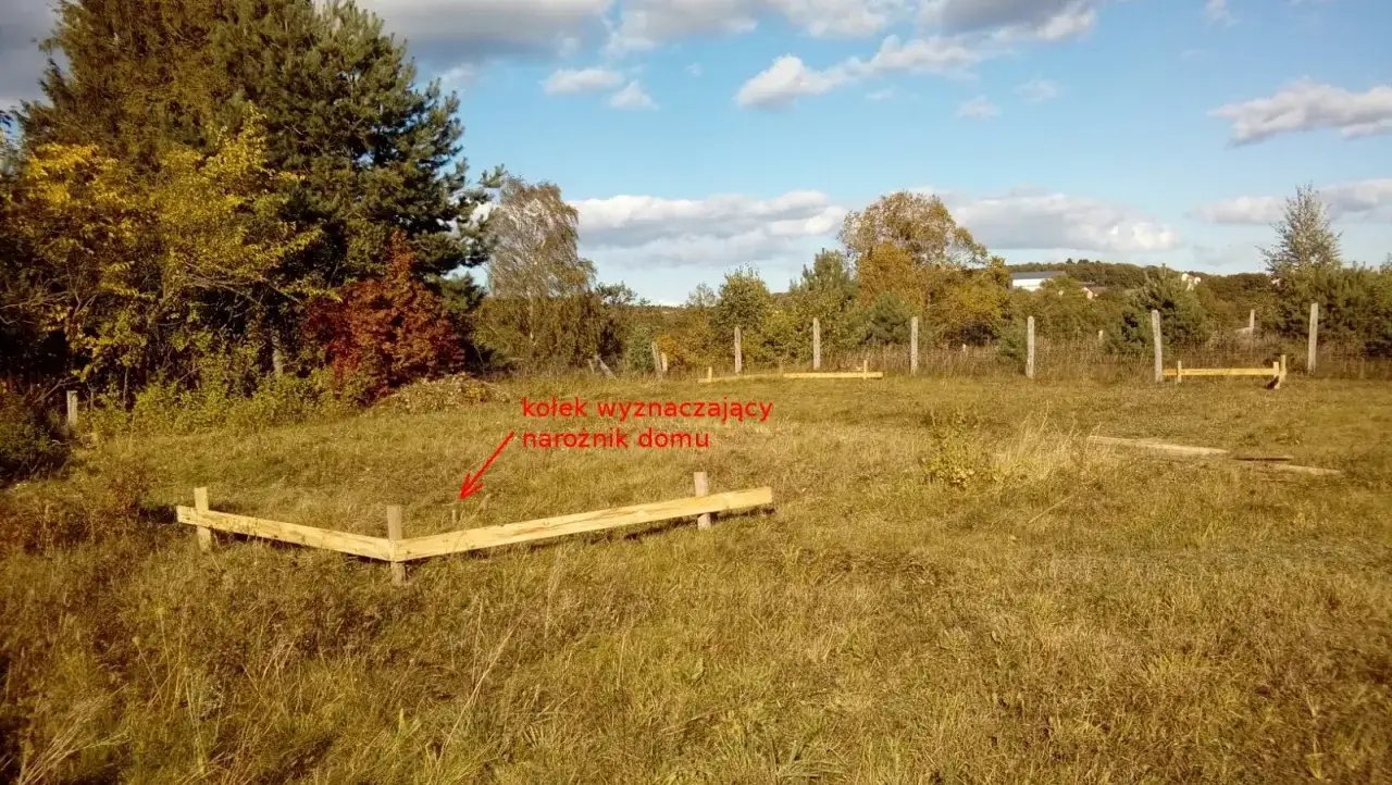 Drewniane deski wyznaczają narożnik domu. To proste, ale skuteczne rozwiązanie, jakie deski do wytyczenia budynku.