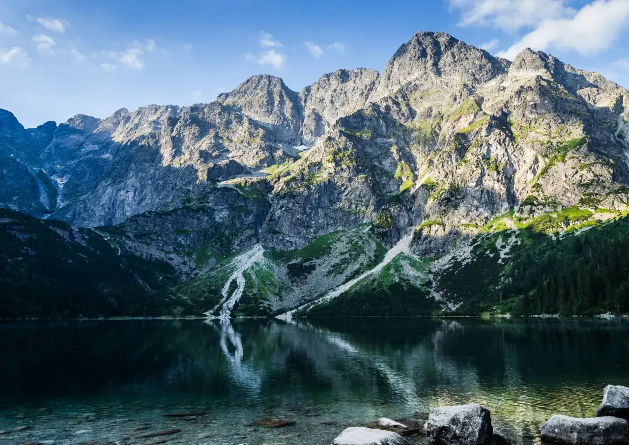 Majestatyczne Tatry, jezioro Morskie Oko odbijające szczyty, zielone zbocza i skalne ściany. Niezapomniane tatry atrakcje.