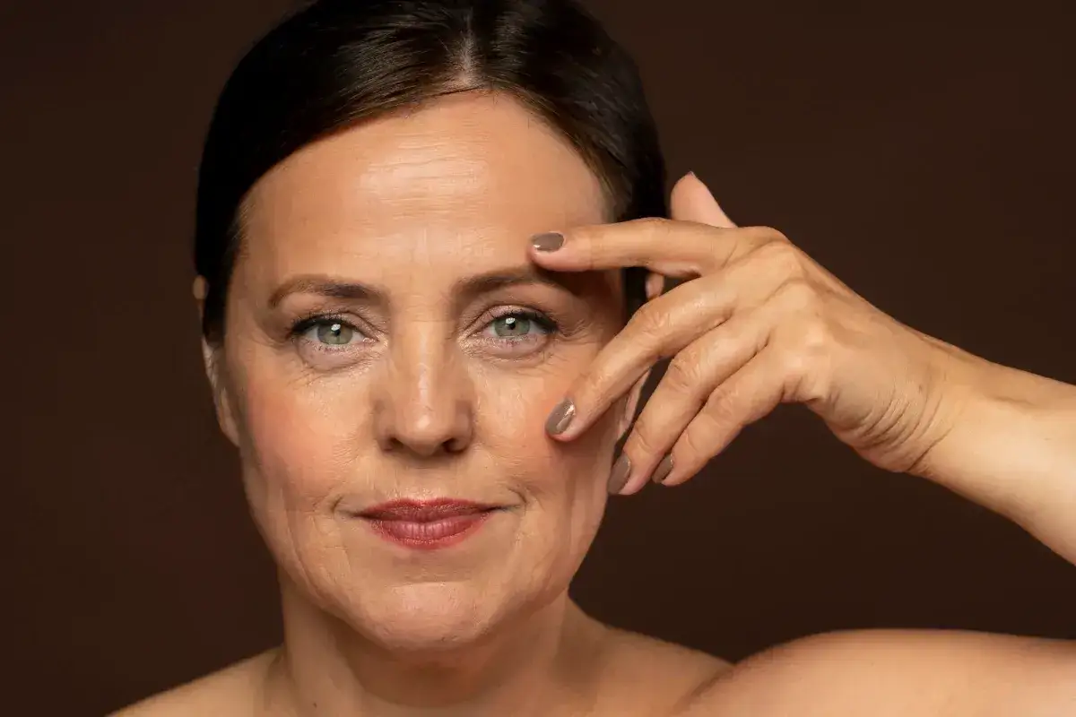 Kobieta w średnim wieku z zadbaną sk&oacute;rą, uśmiechnięta, naturalne światło