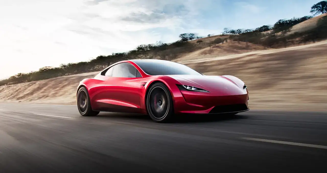 Czerwona Tesla Roadster pędzi po pustynnej drodze. Zastanawiasz się, ile kosztuje najdroższa Tesla?