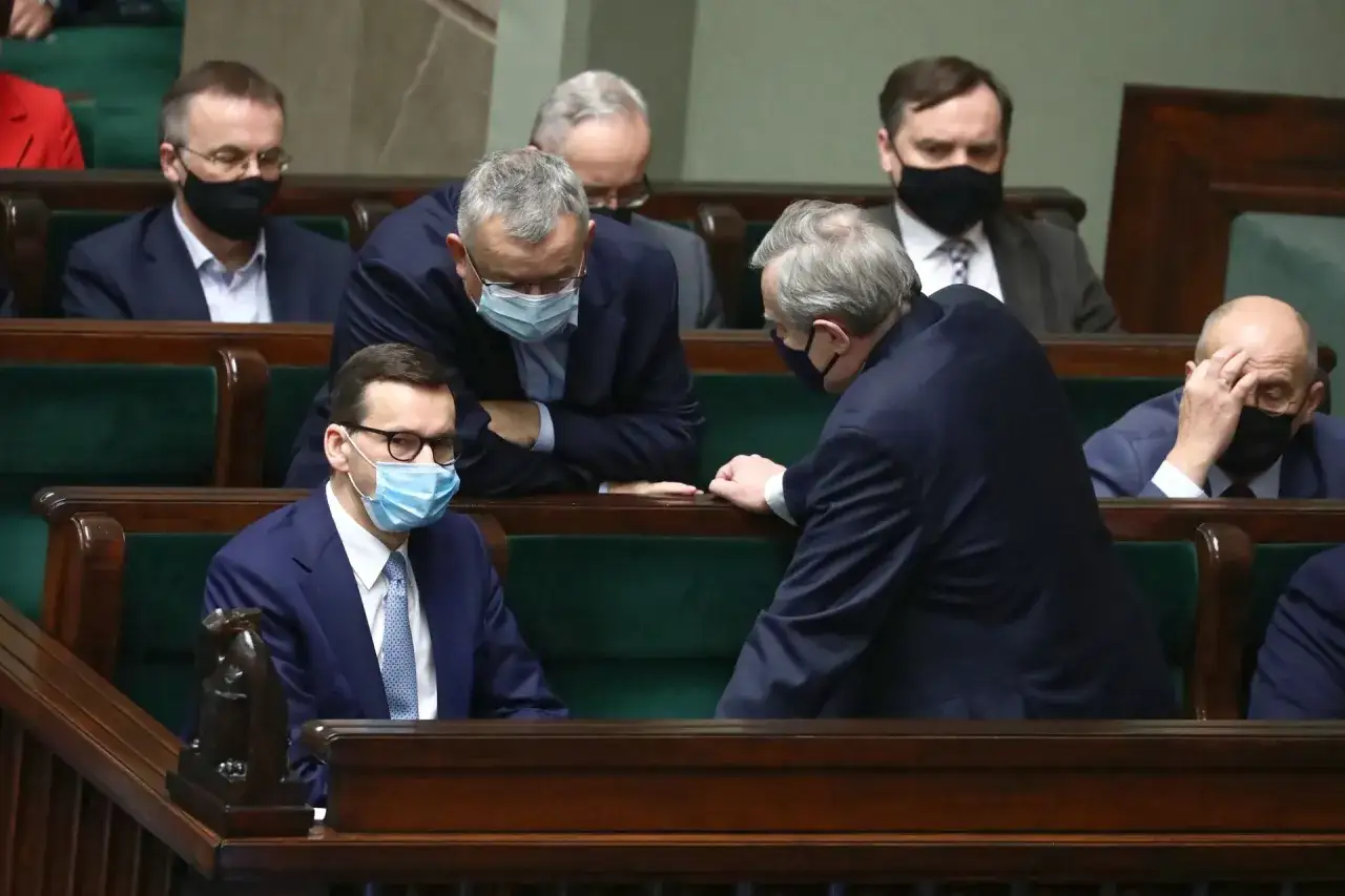 Posłowie w maseczkach dyskutują w ławach sejmowych. W tle widać innych polityków. Tematem rozmowy mogła być ustawa o bezkarności urzędników.