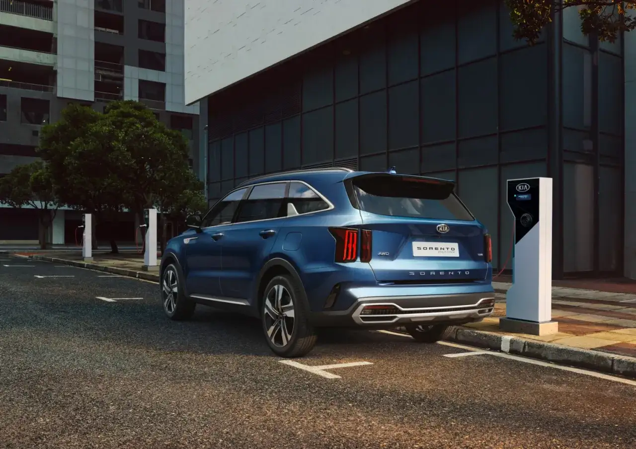 Niebieski Kia Sorento Plug-in Hybrid ładuje się przy stacji ładowania. Poznaj jego imponujące kia sorento wymiary.