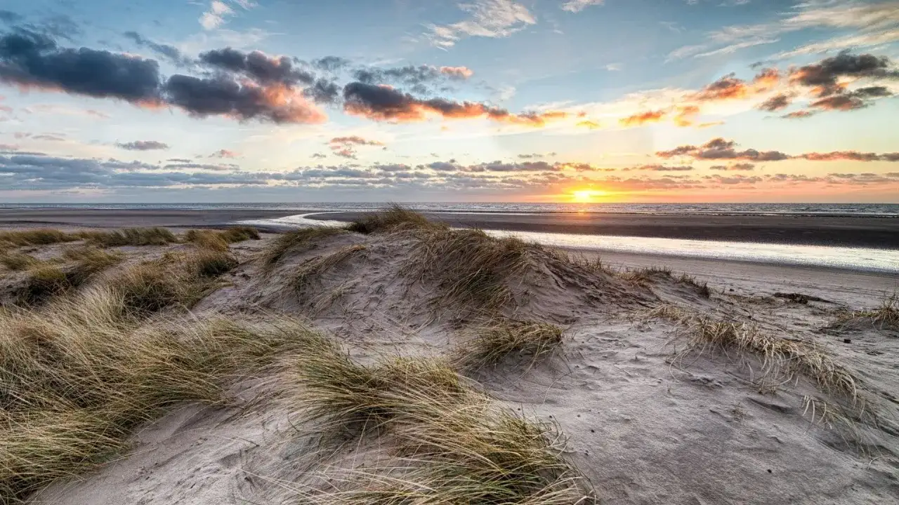 Piękne wczasy dla seniora nad morzem z wyżywieniem. Zachód słońca nad wydmami i morzem, idealne miejsce na relaks.