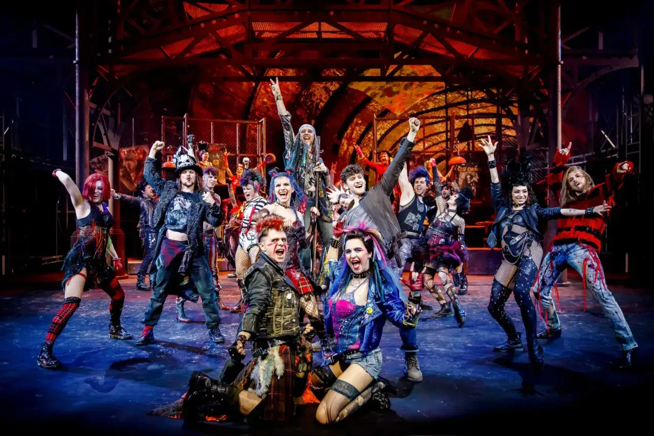 Energetyczny zespół w punkowych strojach świętuje na scenie. To fragment repertuaru teatru Roma, pełen rockowego ducha i młodzieńczej buntu.