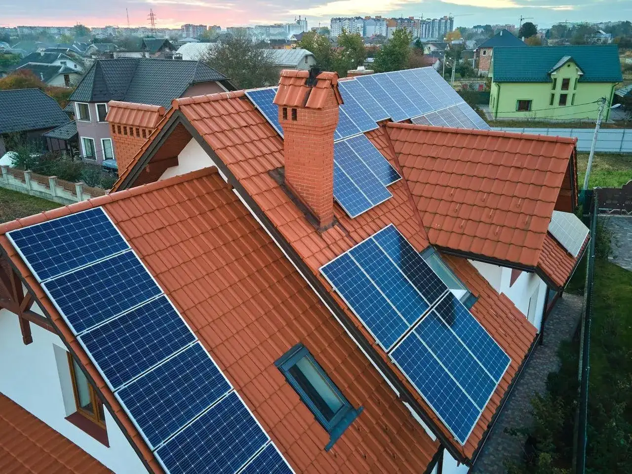 Dachówka i panele słoneczne na dachu domu. To przykład, jak wytworzyć prąd domowym sposobem, wykorzystując energię słoneczną.