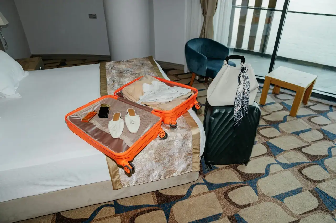 W otwartej walizce leżą perfumy, buty i ubrania. Czy można przewozić perfumy w bagażu rejestrowanym? Tak, zazwyczaj można.