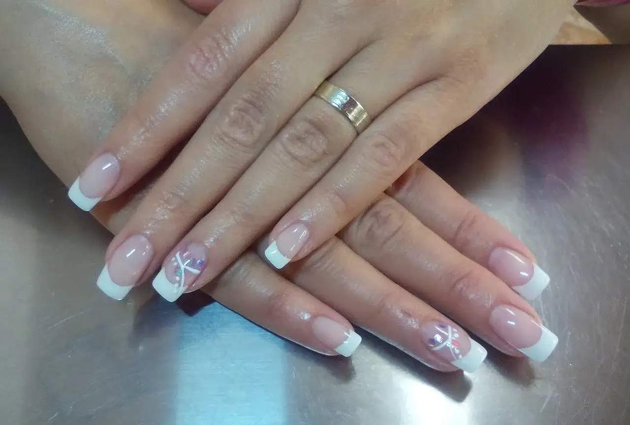 Eleganckie paznokcie żelowe z francuskim manicure i delikatnymi zdobieniami. Dowiedz się, jak nakładać żel na paznokcie, by uzyskać taki efekt.