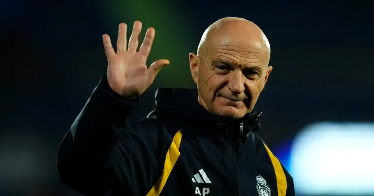 Łysy mężczyzna w kurtce z ż&oacute;łtym pasem macha ręką. To **kitman, kto to**? To osoba odpowiedzialna za sprzęt w drużynie.