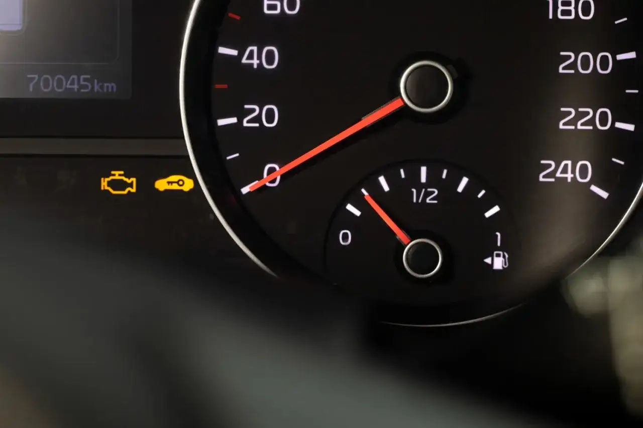 Na desce rozdzielczej świeci się żółta kontrolka check engine, sygnalizując problem z silnikiem. Obok widać wskaźnik paliwa.