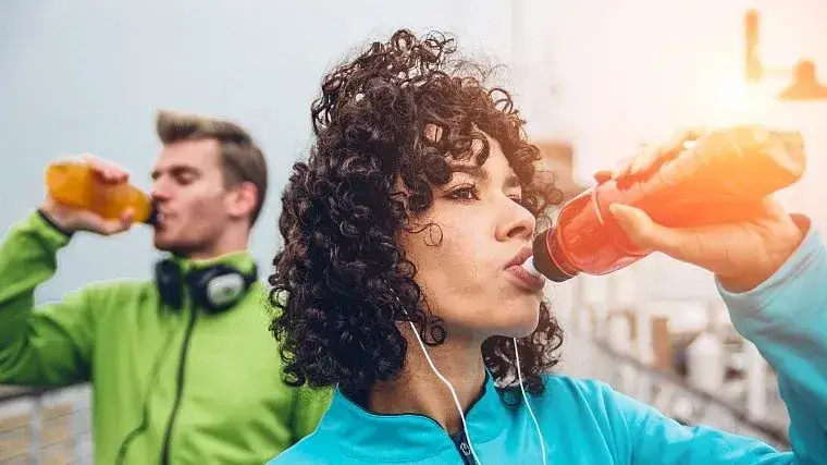Osoba pijąca nap&oacute;j energetyczny przed treningiem