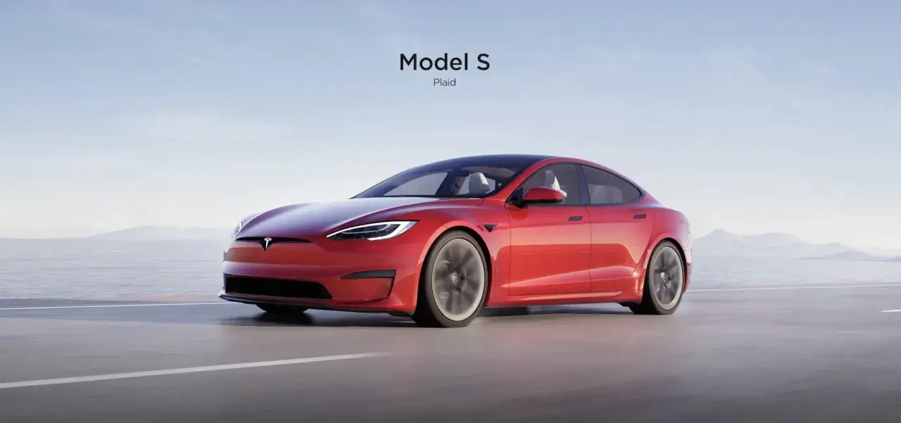 Czerwony Tesla Model S Plaid, z imponującą mocą, pędzi po pustej drodze z widokiem na morze i g&oacute;ry.