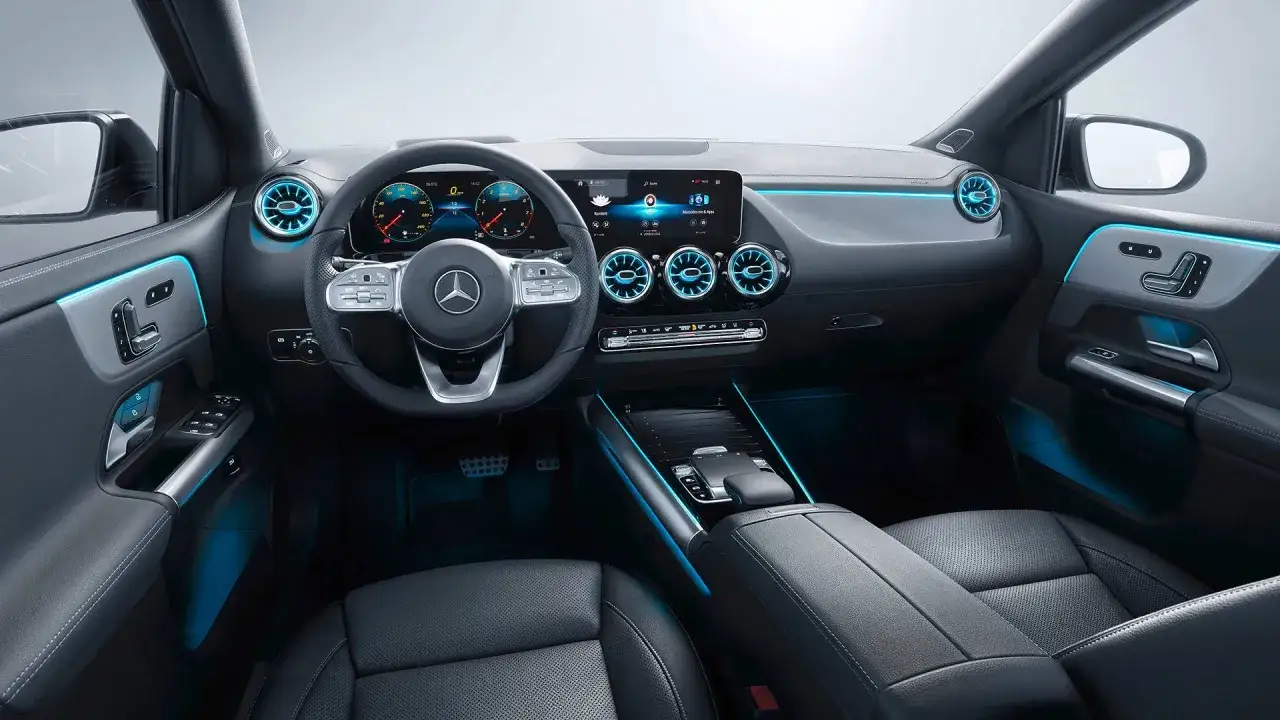 Wnętrze Mercedesa Klasy B, z nowoczesnym kokpitem i niebieskim ambientowym oświetleniem. Opinie o tym modelu często podkreślają jego komfort i technologię.