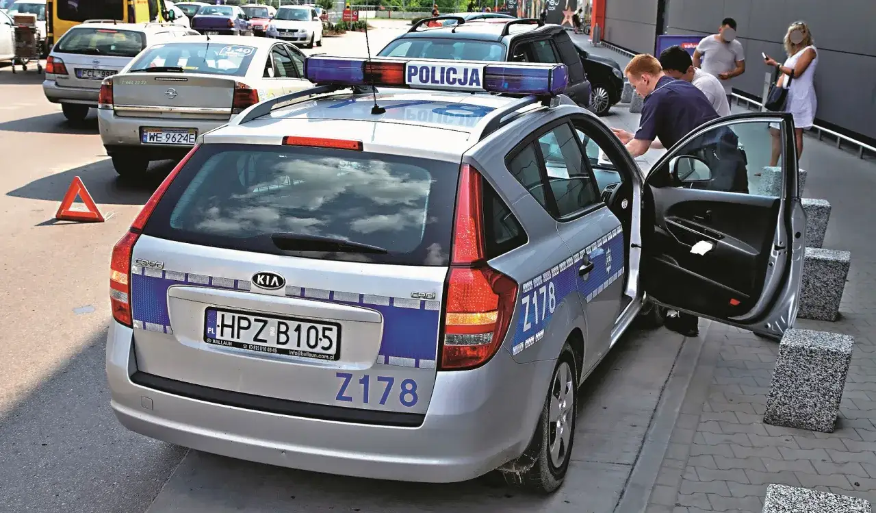 Policja kontroluje drogę wewnętrzną, sprawdzając przepisy. Na zdjęciu radiowóz z włączonym kogutem i funkcjonariuszami.