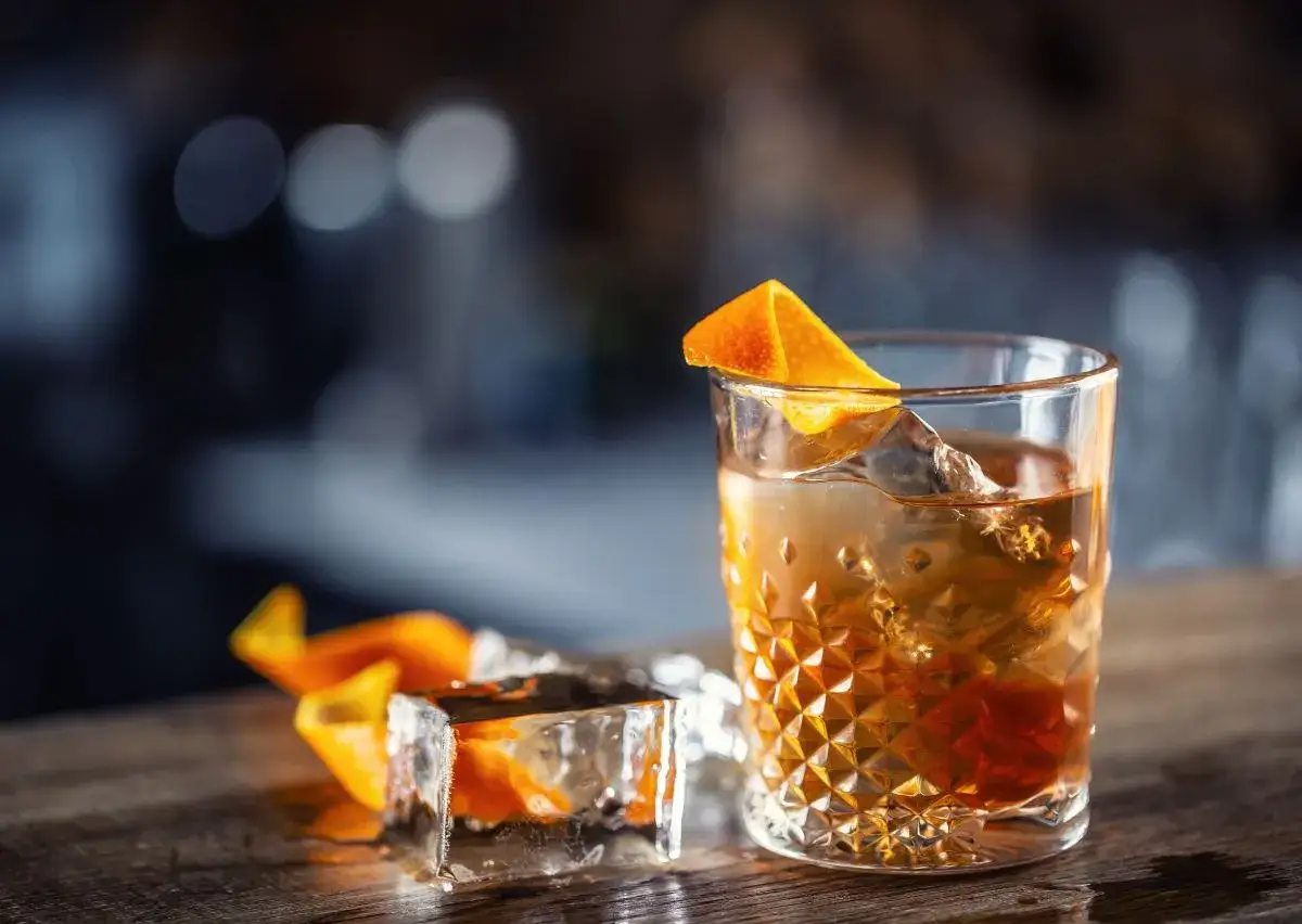Idealne Old Fashioned w domu: wybór bazy i bittersów. Bursztynowy trunek z lodem i skórką pomarańczy.