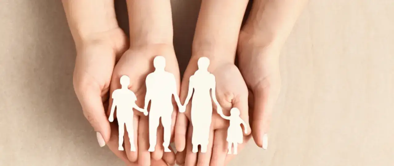 Dłonie trzymają wycięte z papieru postacie rodziny. Zastanawiasz się, ile kosztuje adopcja dziecka w Polsce?