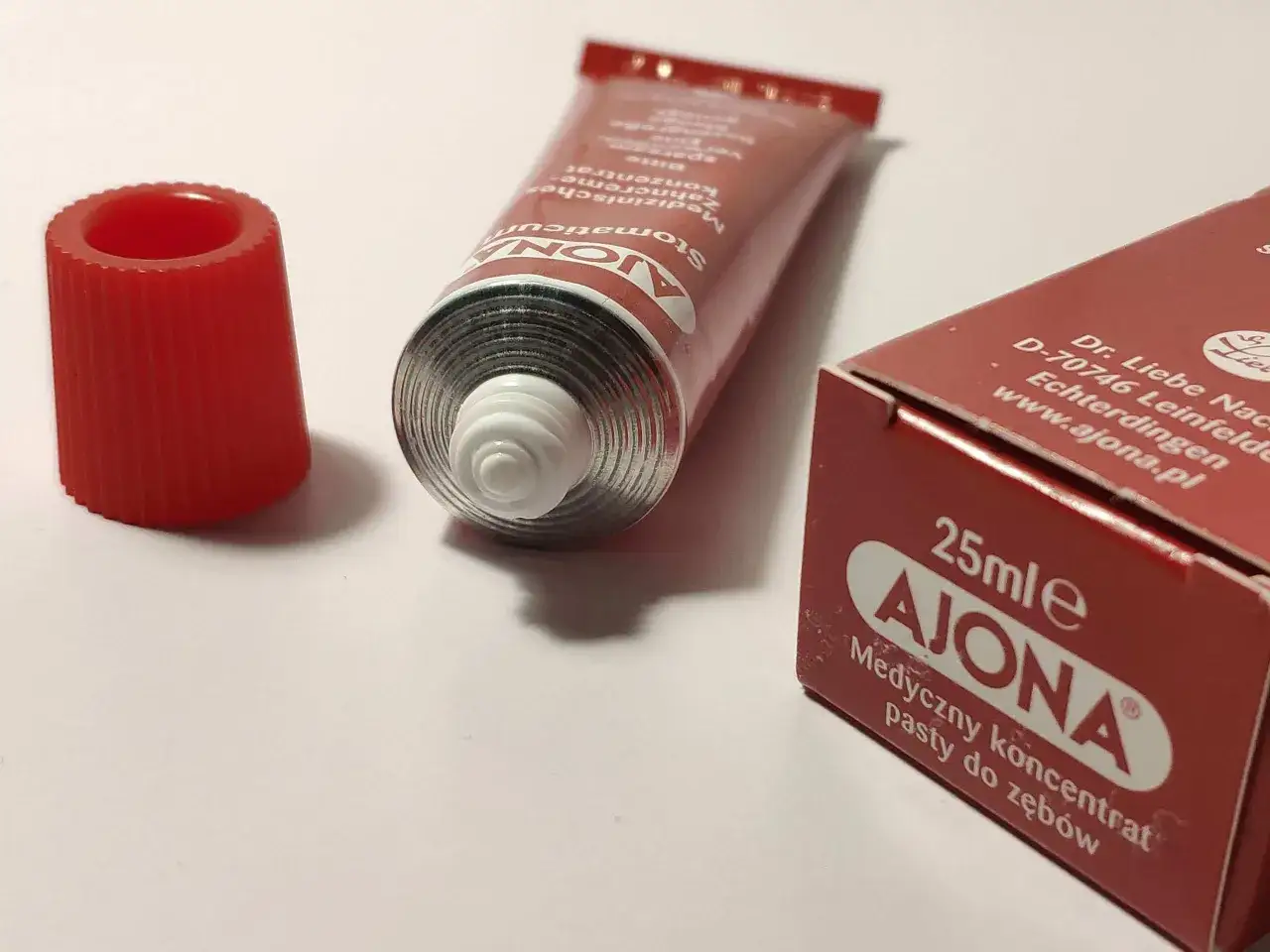 Pasta Ajona, medyczny koncentrat do zębów. Zastanawiasz się nad jej skutkami ubocznymi? Tubka i opakowanie na białym tle.