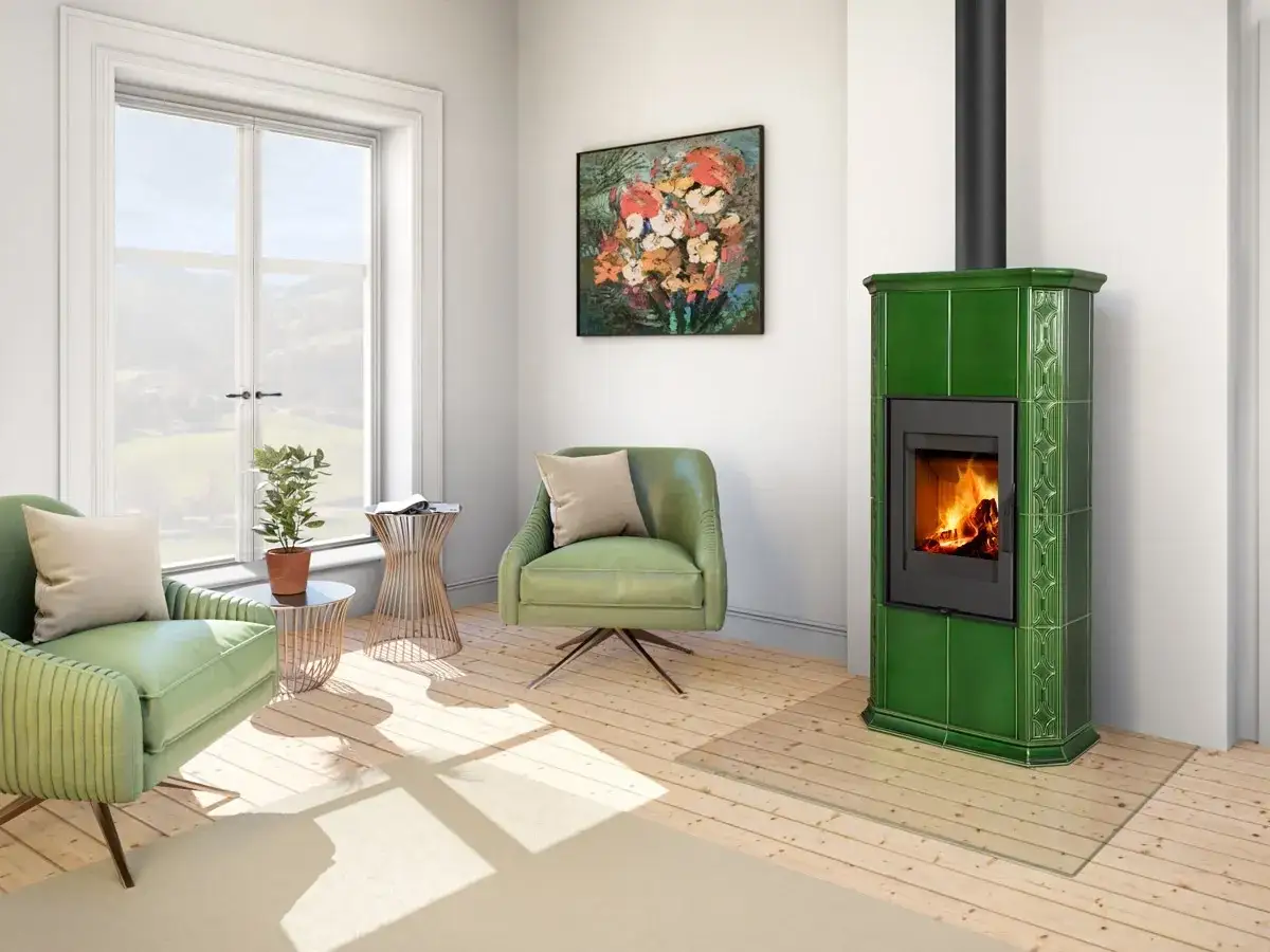Zielony, wolnostojący kominek bez zabudowy z palącym się ogniem, obok zielonych foteli i obrazu z kwiatami.