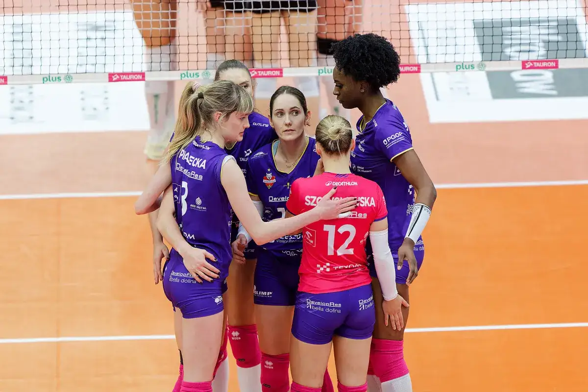 Siatkarki w fioletowych strojach przytulają się przed meczem. Ich stroje sugerują, że walczą o wysokie miejsca w lidze mistrzyń siatkówka tabela.