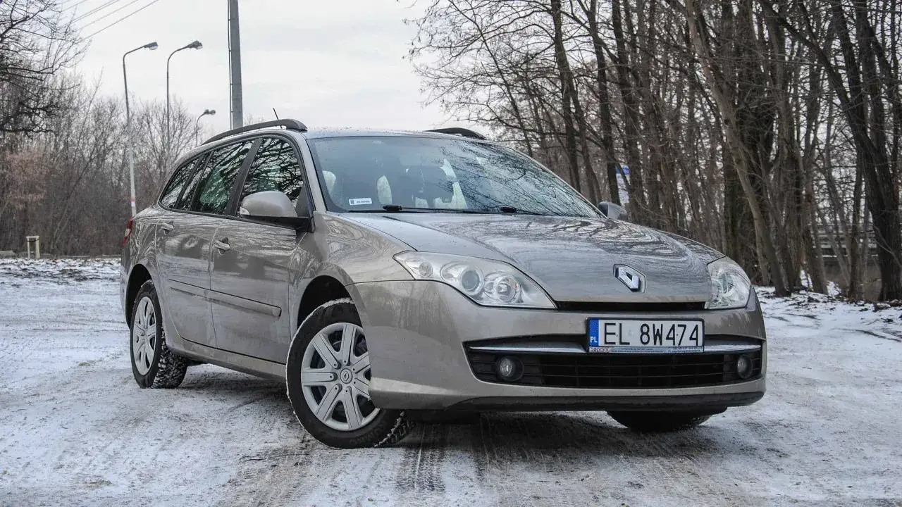 Srebrne kombi Renault Laguna 3 na zaśnieżonej drodze, otoczone zimowym lasem.