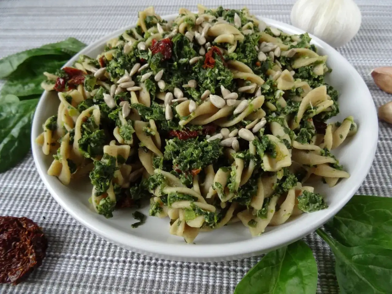 Pyszny makaron ze szpinakiem i suszonymi pomidorami, posypany słonecznikiem. Idealny na szybki obiad.