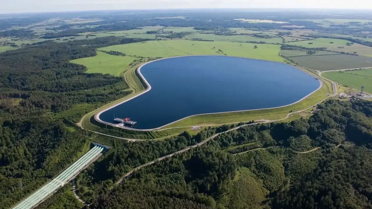 Zbiornik szczytowy elektrowni szczytowo-pompowej w Polsce, otoczony lasami i polami. Potężne rury transportują wodę, pokazując skalę tej inwestycji.