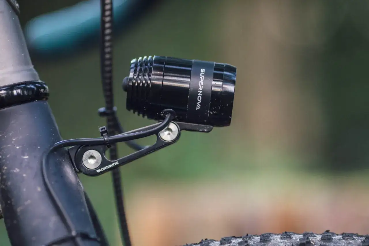 Czarny reflektor Supernova zamontowany na rowerze. Pokazuje, jak włączyć dynamo w rowerze, zapewniając światło podczas jazdy.