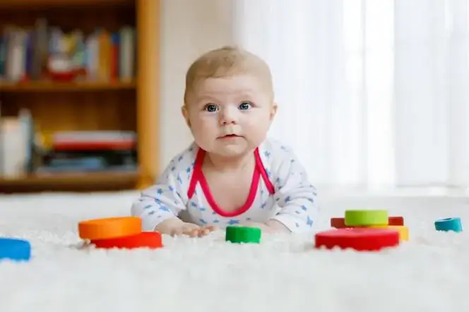 4 miesięczne dziecko bawi się grzechotką i uśmiecha