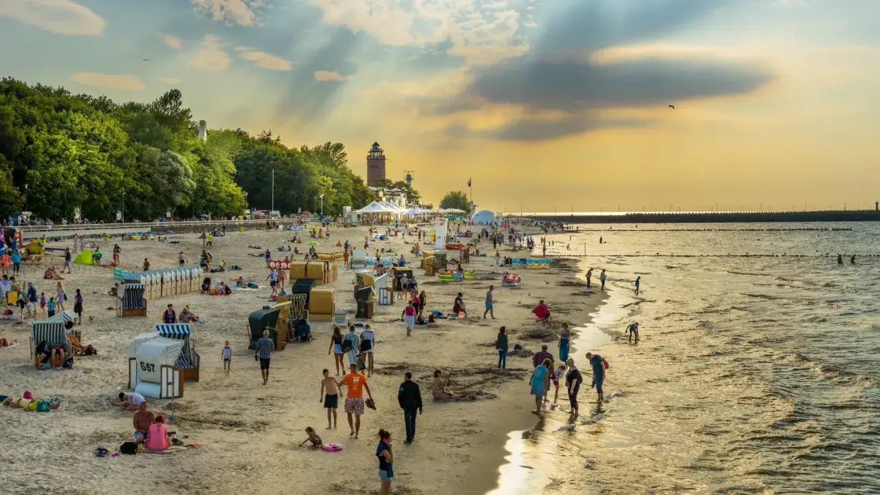 Zachód słońca na plaży w Kołobrzegu. Tłumy ludzi, parawany, budki plażowe. Zastanawiasz się, ile kosztuje klimatyczne w Kołobrzegu?