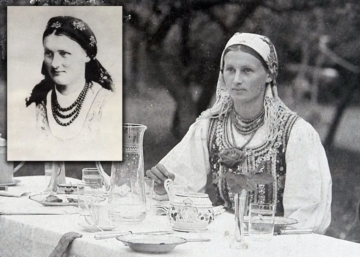 Lucjan Rydel i Jadwiga Mikołajczyk&oacute;wna na tle stołu z zastawą. Jadwiga w tradycyjnym stroju z naszyjnikami.
