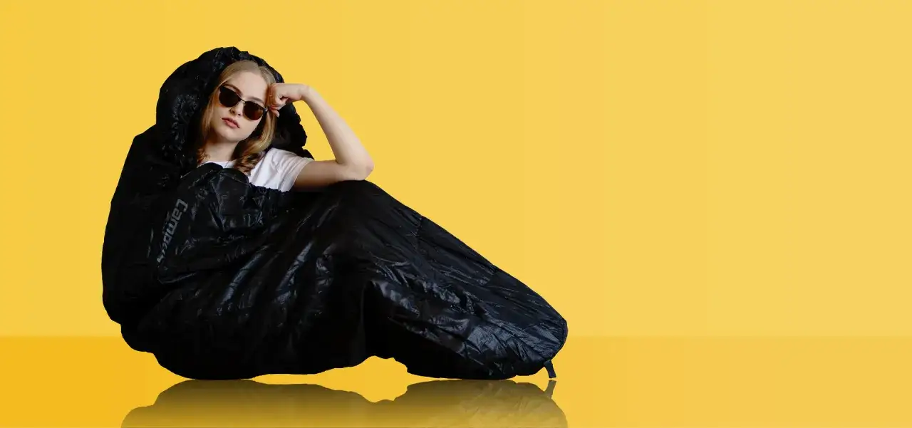 Dziewczyna w okularach przeciwsłonecznych, owinięta w czarny śpiw&oacute;r, wygląda jakby zastanawiała się, jak prać śpiw&oacute;r.