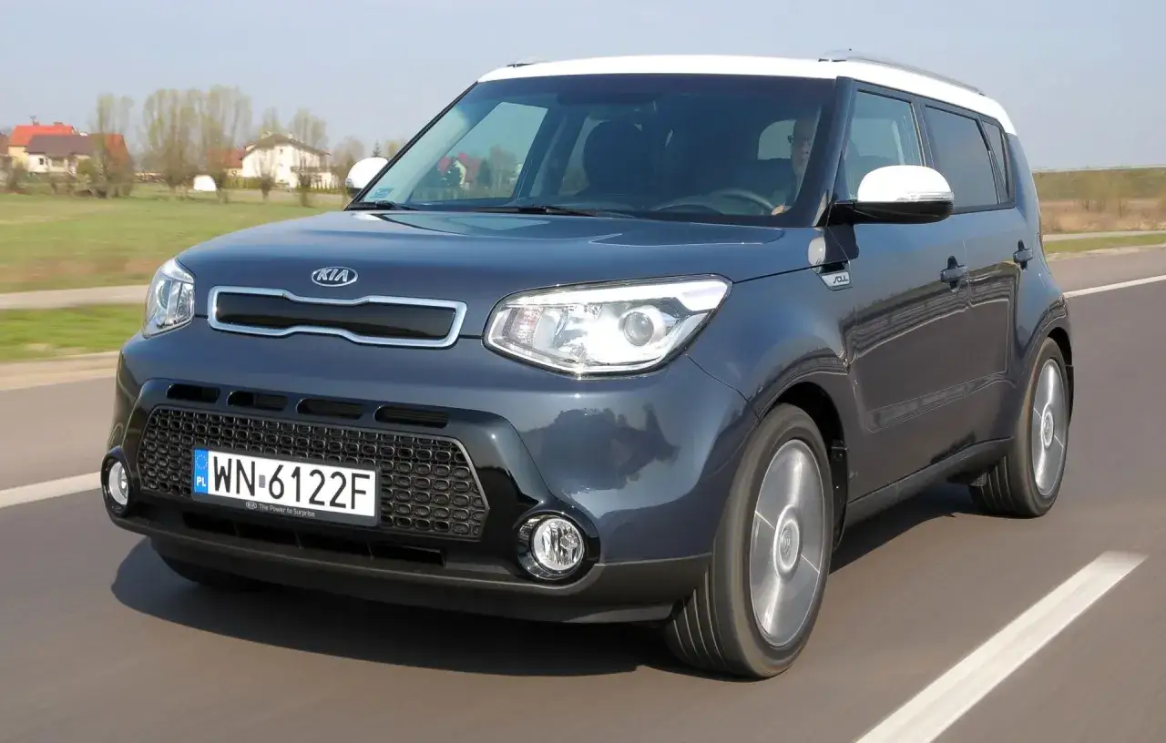 Ciemnoszary Kia Soul z białym dachem jedzie po drodze.