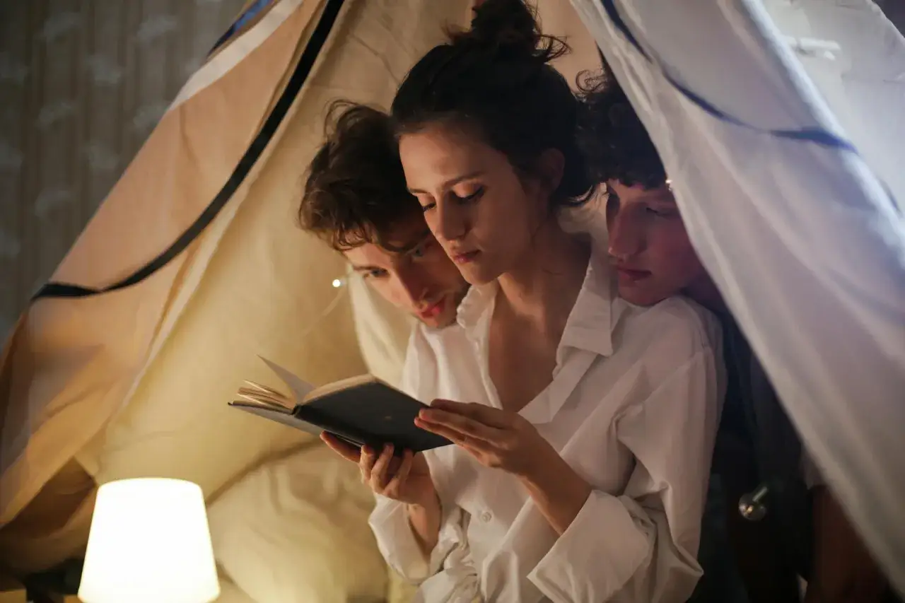 Trzy osoby czytają książkę pod kocem. Czy to przykład nie monogamii, co to znaczy?