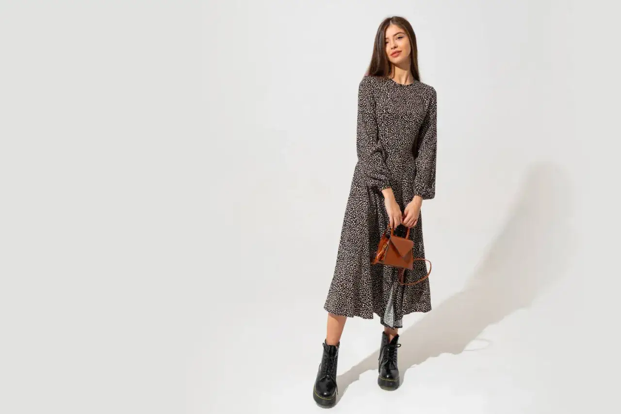 Modelka w długiej, wzorzystej sukience i czarnych botkach. Stylowe buty do długiej sukienki dodają charakteru.